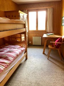 a bedroom with bunk beds and a table and a desk at Alpenchalet Trutmundi undri in Eischoll