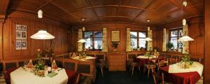 a dining room with two tables and chairs and windows at Pension Backstuba in Partenen