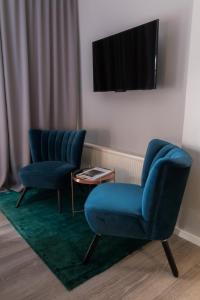 Cette chambre comprend 2 chaises bleues et une télévision. dans l'établissement rugs HOTEL Köln, à Cologne