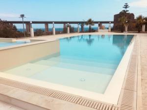 a large swimming pool with blue water at Agriturismo Villa Orchidea in Alì Terme +26 photos