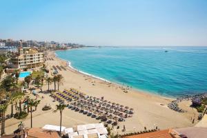 uma praia com um monte de guarda-sóis e o oceano em Sunset Beach Club Hotel Apartments em Benalmádena