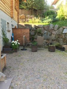 d'une terrasse avec 2 chaises et un mur en pierre. dans l'établissement Le Syote, à Xonrupt-Longemer