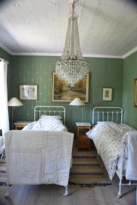 a bedroom with two beds and a chandelier at Brunnbäcks Herrgård in Mästerbo