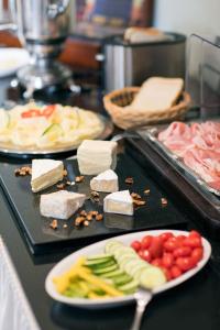 a table with a plate of food with cheese and vegetables at Hotel Widhof - Check-in im Hotel Nibelungenhof in Tulln