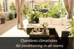 an outdoor patio with a white couch and plants at Logis Hotel - Le Charleston in Le Mans