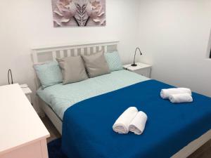 een slaapkamer met een blauw bed en handdoeken bij alojamento Xa andar in Nazaré