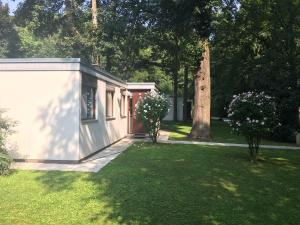 een klein wit gebouw in een tuin met een boom bij Schlosspark Bungalow in Seebenstein