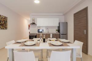 a white dining room table with white chairs in a kitchen at Blubay Apartments by ST Hotels in Il-Gżira