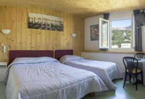 1 dormitorio con 2 camas, mesa y ventana en Hôtel De Paris en Briançon