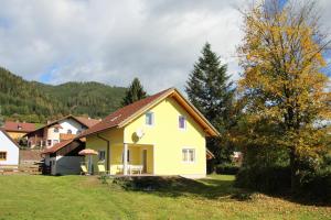 une maison jaune avec un toit marron sur un champ dans l'établissement Narrenhaus, à Fohnsdorf