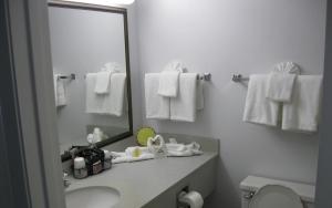 y baño con lavabo, espejo y toallas. en Days Inn by Wyndham Daytona Oceanfront, en Daytona Beach