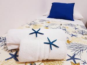 een bed met handdoeken en een blauw kussen bij Guest House San Vito Lo Capo in San Vito lo Capo