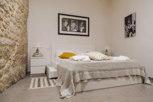 a white bedroom with a bed and a stone wall at Sunset Studio in Scicli