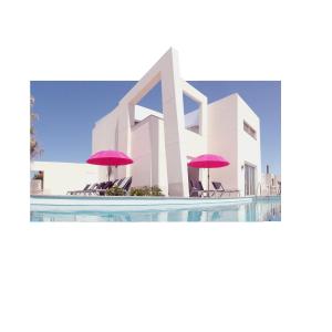 d'un bâtiment avec des parasols roses et une piscine dans l'établissement Villa Royale Trespalomas, à Maspalomas