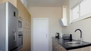 a kitchen with a sink and a refrigerator at VillasRoyale Trespalomas - An Iconic Villa for Elevated Getaways! in Meloneras
