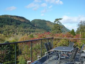 a table and chairs on a balcony with mountains at Maes-y-Garth in Betws-y-coed