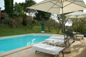 a swimming pool with two chairs and an umbrella at Tenuta Merlano in Sacrofano