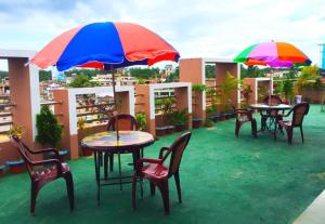 een groep tafels en stoelen met parasols op een dak bij Hotel Skypark, Sreemangal in Sreemangal