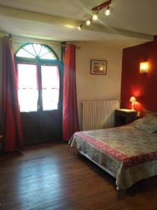 a bedroom with a bed and a window with red curtains at Auberge de La Halle in Cordes-sur-Ciel