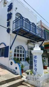 een wit gebouw met een blauw balkon bij Nandian Homestay in Eluan