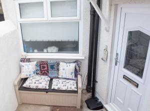 a porch with pillows on a bench next to a door at Sefton Cottage in Deganwy