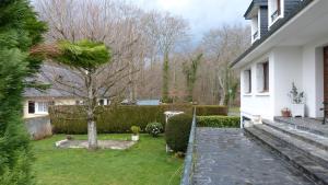 een tuin met een boom en een wit huis bij Chambres d'Hôtes La Plantade in La Barthe-de-Neste