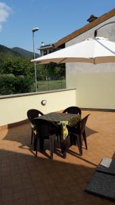 B&B I Lazzarini في سارنيكو: طاولة وكراسي مع مظلة على الفناء