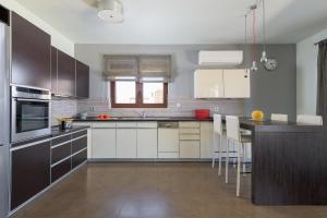 uma cozinha com armários brancos e um balcão preto em Alav Pool Villa em Afantou