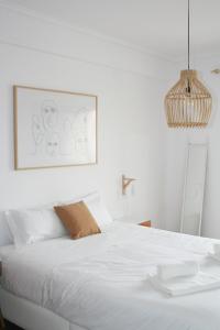 Un dormitorio con una cama blanca con una foto en la pared en Gare Do Sol, en Aveiro
