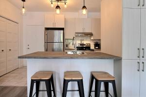 a kitchen with a counter with two stools in it at INITIAL - PILOTE - Centre-Ville de Québec in Quebec City