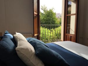 un letto con lenzuola e cuscini blu di fronte a una finestra di Apartamentos Viejo Continente a Cuenca