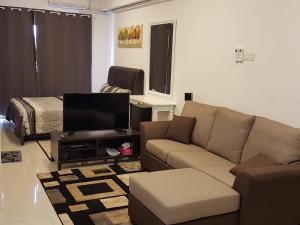 uma sala de estar com um sofá e uma televisão de ecrã plano em SJA Suria Jelutong em Shah Alam