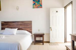 - une chambre avec un lit blanc et une tête de lit en bois dans l'établissement Bungalows Zicatela, à Puerto Escondido