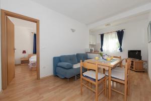 a living room with a table and a blue couch at Apartments IVO in Tučepi
