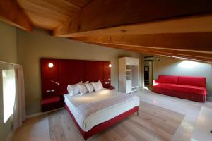 una camera con un grande letto e un divano rosso di Le Greghe Suites a Lazise