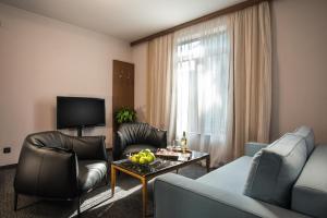 een woonkamer met een bank, stoelen en een tafel bij Uniqato Hotel in Stara Zagora