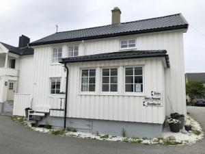 a white house with a bench in front of it at Olsens Pensjonat in Veiholmen