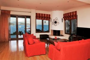 a living room with red chairs and a television at Poseidon villa m ammos in Skiathos