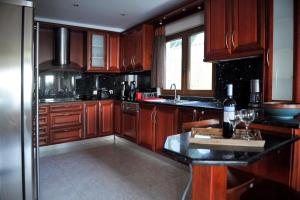 a kitchen with wooden cabinets and a black counter top at Poseidon villa m ammos in Skiathos
