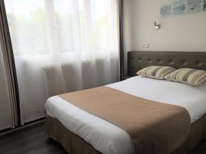 a bed in a room with a large window at Auberge Les Mufliers - Hôtel Les Forges in Pontenx-les-Forges