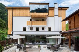 a building with a balcony with tables and chairs at Naturhotel Rainer in Racines