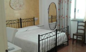 a bedroom with a bed with a mirror and a chair at Pensione S. Antonio Ristorante Silvia in Furci Siculo