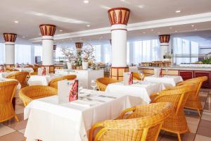 a restaurant with white tables and wicker chairs at Grupotel Santa Eulària & Spa - Adults Only in Santa Eularia des Riu