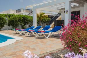 a row of blue lounge chairs next to a swimming pool at Villas Susaeta in Playa Blanca