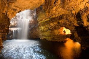 a waterfall in a cave with a body of water at Durness Youth Hostel in Durness