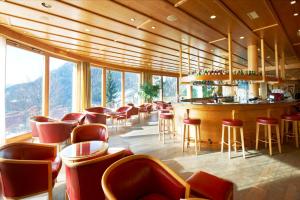 a restaurant with a bar with a view of the mountains at Hôtel des Bains d'Ovronnaz in Ovronnaz