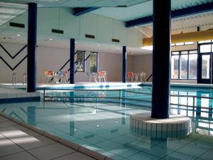 a large swimming pool with chairs in a building at Wittegrijzeduinen in Hollum