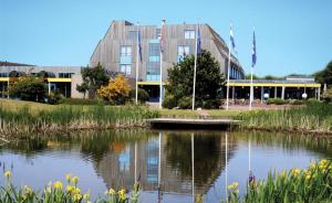 un edificio con un lago frente a él en Wittegrijzeduinen, en Hollum