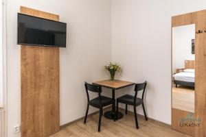 a small table with two chairs and a television on a wall at Ubytovna U Kašny in Uherské Hradiště