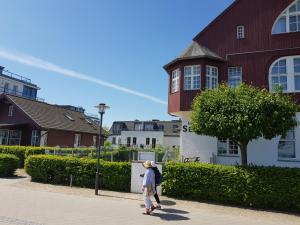 a woman walking down a sidewalk near a building at Seeblickstudio 2.33 im Seehof Bansin in Bansin